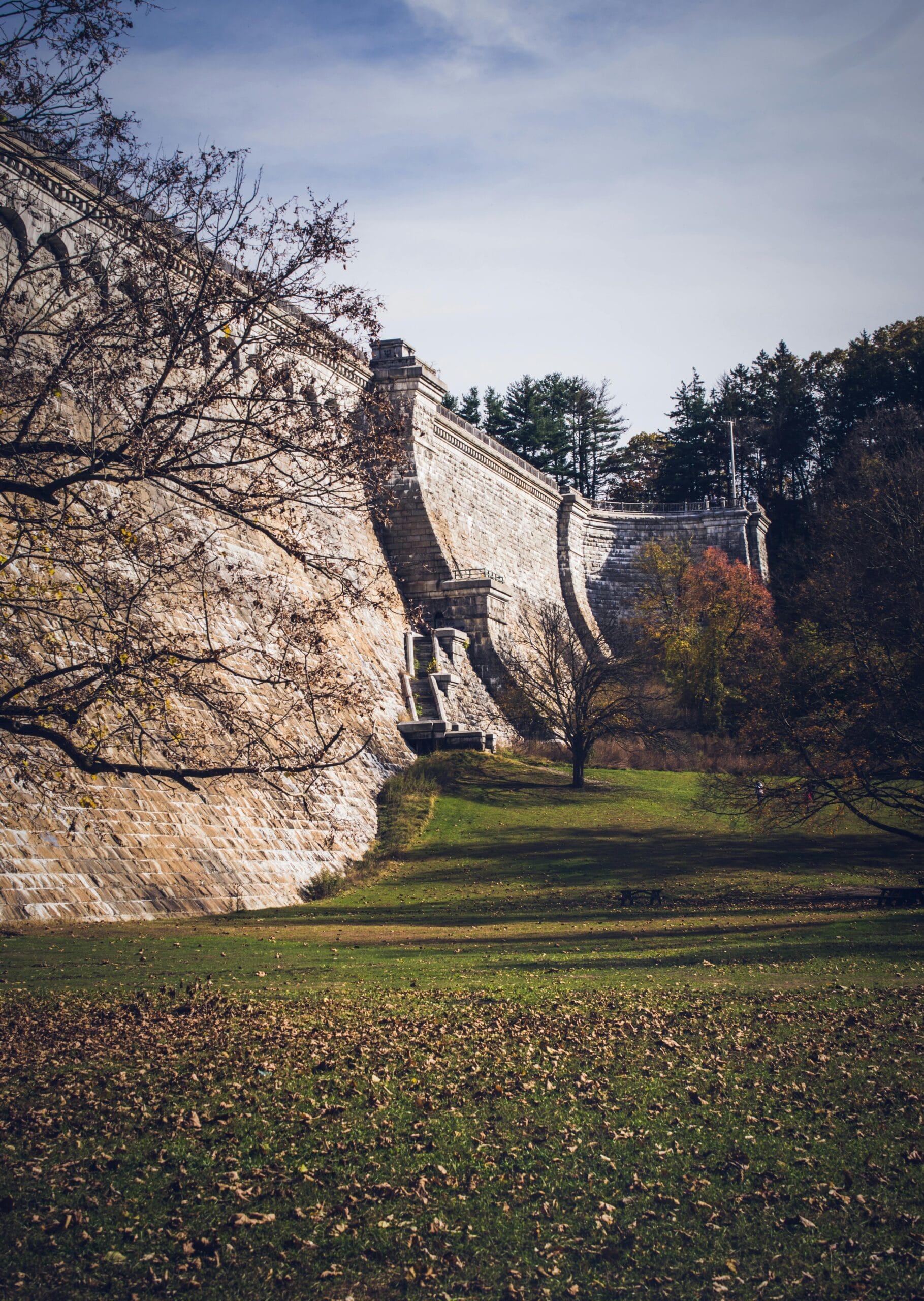 New Croton Dam’s curved stone wall surrounded by fall foliage in Westchester County, NY.
