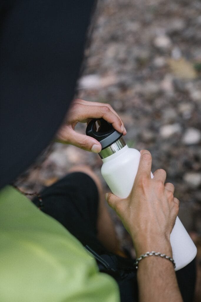 a person opening a white metal water bottle